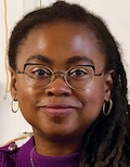 Jamia Wilson, a Black woman with glasses, smiles with closed lips.