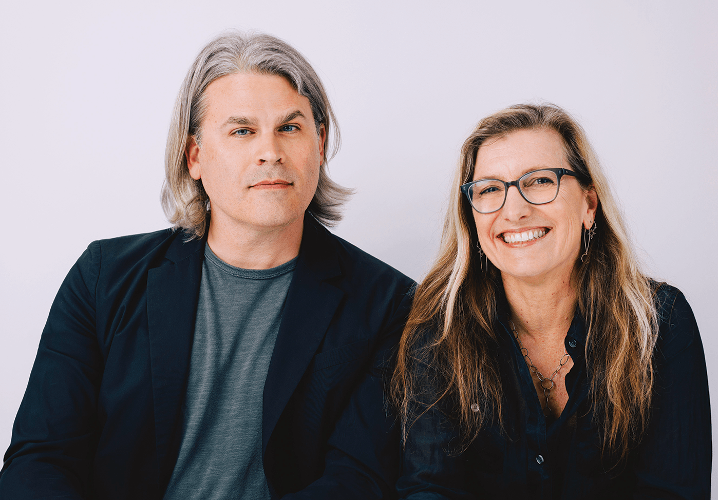 Indoor photo portrait of man in dark blazer and woman wearing dark shirt