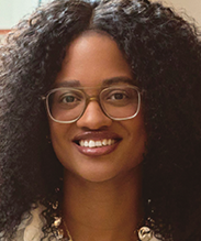 Close-up photo portrait of a smiling woman with long curly hair and eyeglasses