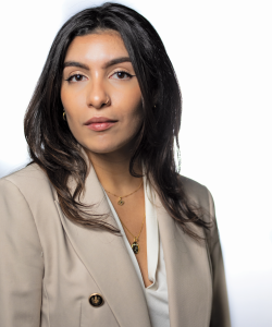 The Next Great Agents: Six Rising Stars on Advocacy, Artistry, and What’s Ahead A photo portrait of Angeline Rodriguez, a Latina woman with tan skin and layered brown hair. She wears a beige blazer and two delicate gold necklaces with a white blouse underneath.