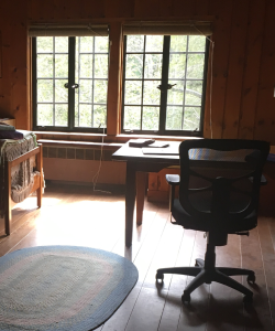 Indoor photograph of a wood-paneled room with a window, desk, and rugs