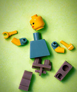 A deconstructed lego person is spread out on a light green surface.