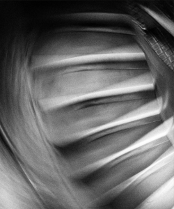 A black-and-white photo of a staircase. The camera appears to have been moved or shaken during the exposure, creating a blurry, disorienting effect.