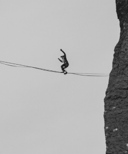 A person, arms raised, balances on a tightrope far above the ground in Smith Rock State Park in Oregon.
