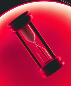 An hourglass sand timer is illuminated by red light. An hourglass sand timer is illuminated by red light.