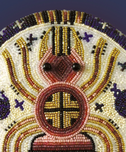 Close-up of the cover of Joy Harjo’s Poet Warrior. An intricate piece of beadwork depicts a spider. The body of the spider is rendered in red and gold beads, while its legs are gold and brown.