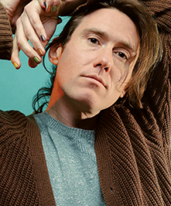 A photo of the author with his arms resting on his head. Alex McElroy