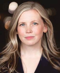 Photo portrait of a woman with long blonde hair in front of a dark background with blurred lights  