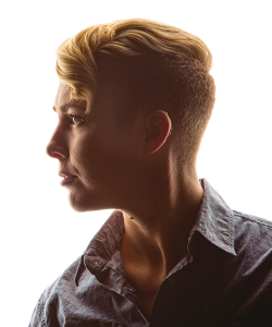 Professional photo profile portrait of a person with short blonde hair, longer on top, and a Western-style denim-color shirt 