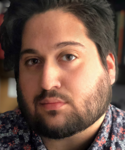 A close-up photo portrait of Steven Espada Dawson, a young man with dark brown hair, medium skin, and brown eyes. He wears a blue patterned floral shirt and his hair is combed over to one side. A bookshelf can be seen in the background.