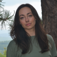 Head shot of Rachel Dillon Head shot of Rachel Dillon, standing outside next to a pine tree with hills in the background