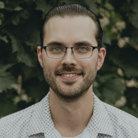 Head shot of Luke Hankins, a person with dark hair, glasses, and a beard who is smiling for the camera