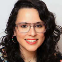 Headshot of Joanna Volpe Headshot of Joanna Volpe, smiling, wearing glasses and colorful hoop earrings