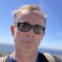Headshot of William D. Waltz Headshot of William D. Waltz, wearing sunglasses as he hikes in the sun