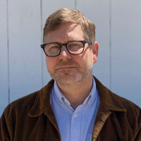 Head shot of Wayne Miller Head shot of Wayner Miller, standing outside in front of a pale blue wall