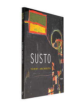 A photo of the final version of Susto, a thin poetry book featuring colorful abstract art on the front cover on a dark background.
